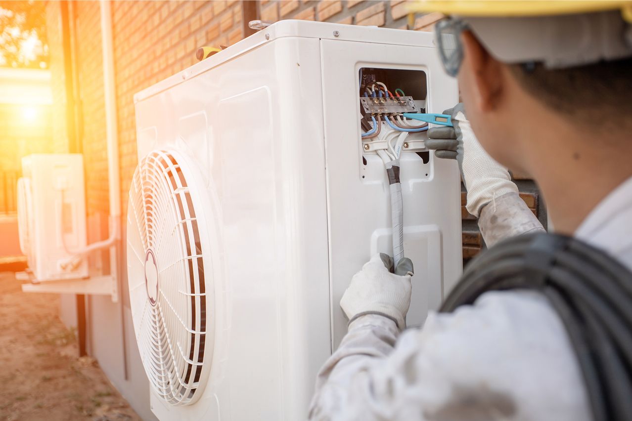 Techniker installiert eine Klimaanlage an einer Wand.